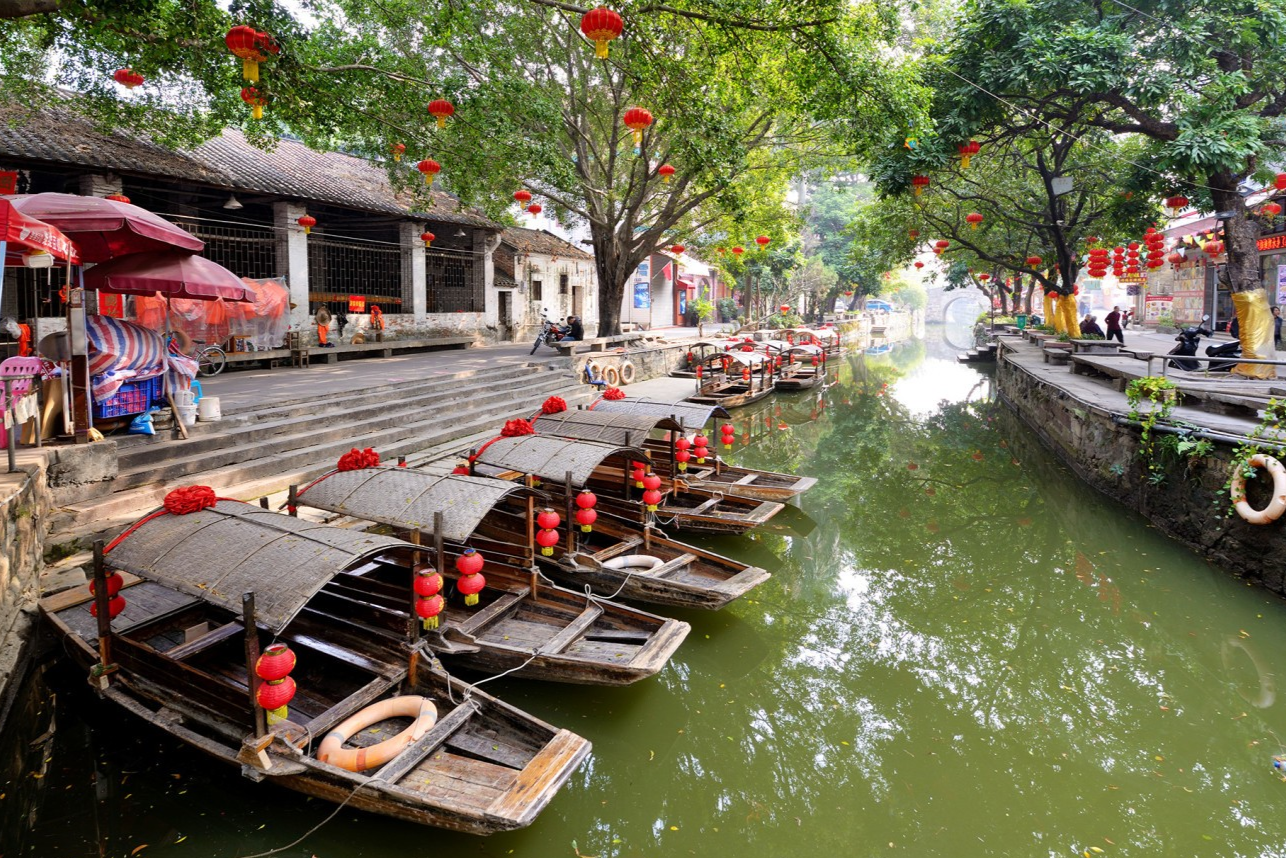  A boatman poling a sampan along a canal in Fengjian, with tourists aboard
