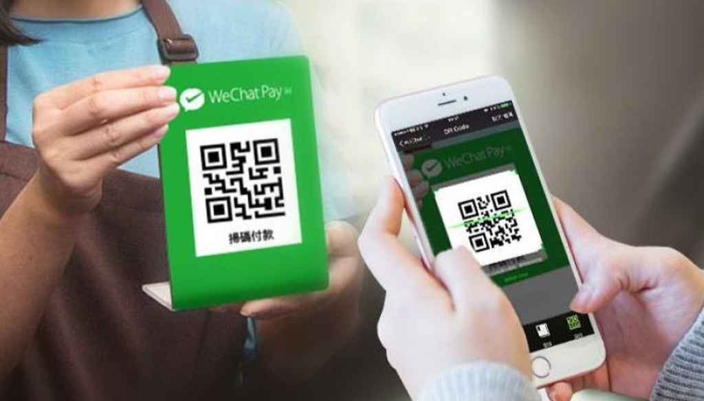A busy Chinese street market showing vendors with QR codes for mobile payments