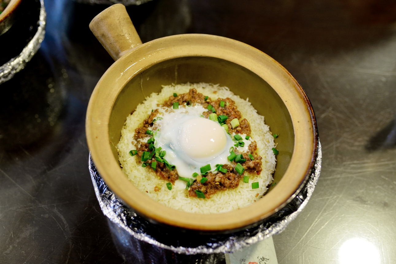  A steaming pot of Beef with Raw Egg Clay Pot Rice, with the egg just added or being mixed