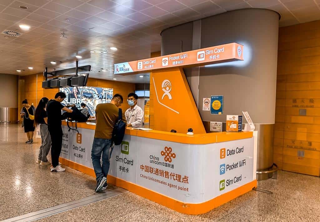 Airport SIM card kiosk with staff assisting travelers
