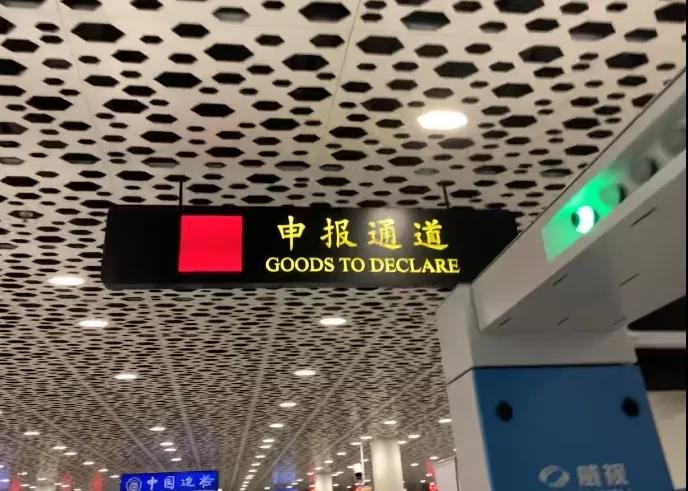 Clear signage at Chinese airport showing red and green customs channels
