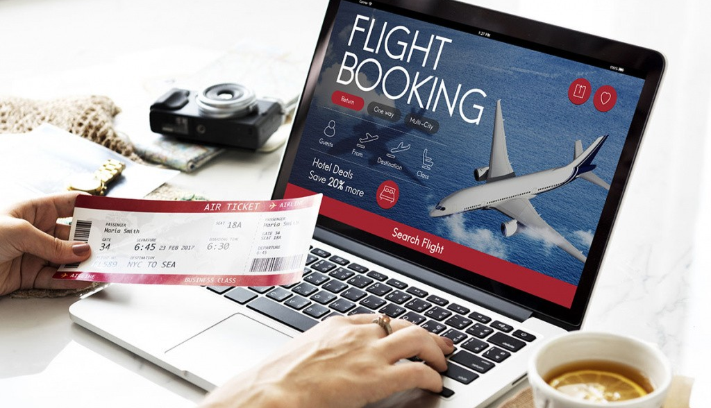Person comparing flight prices on laptop and mobile phone