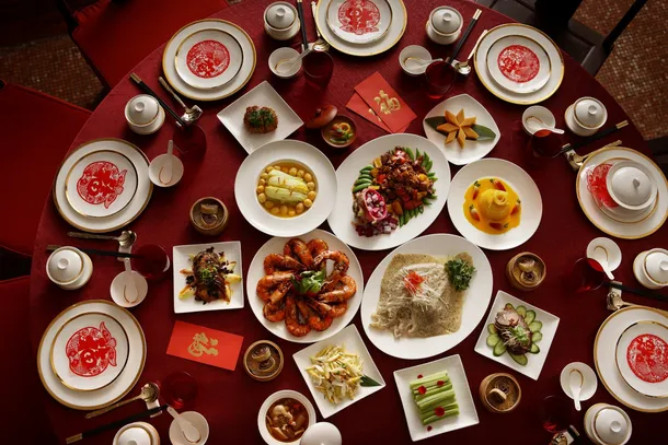 Traditional Chinese banquet table with multiple dishes and happy diners