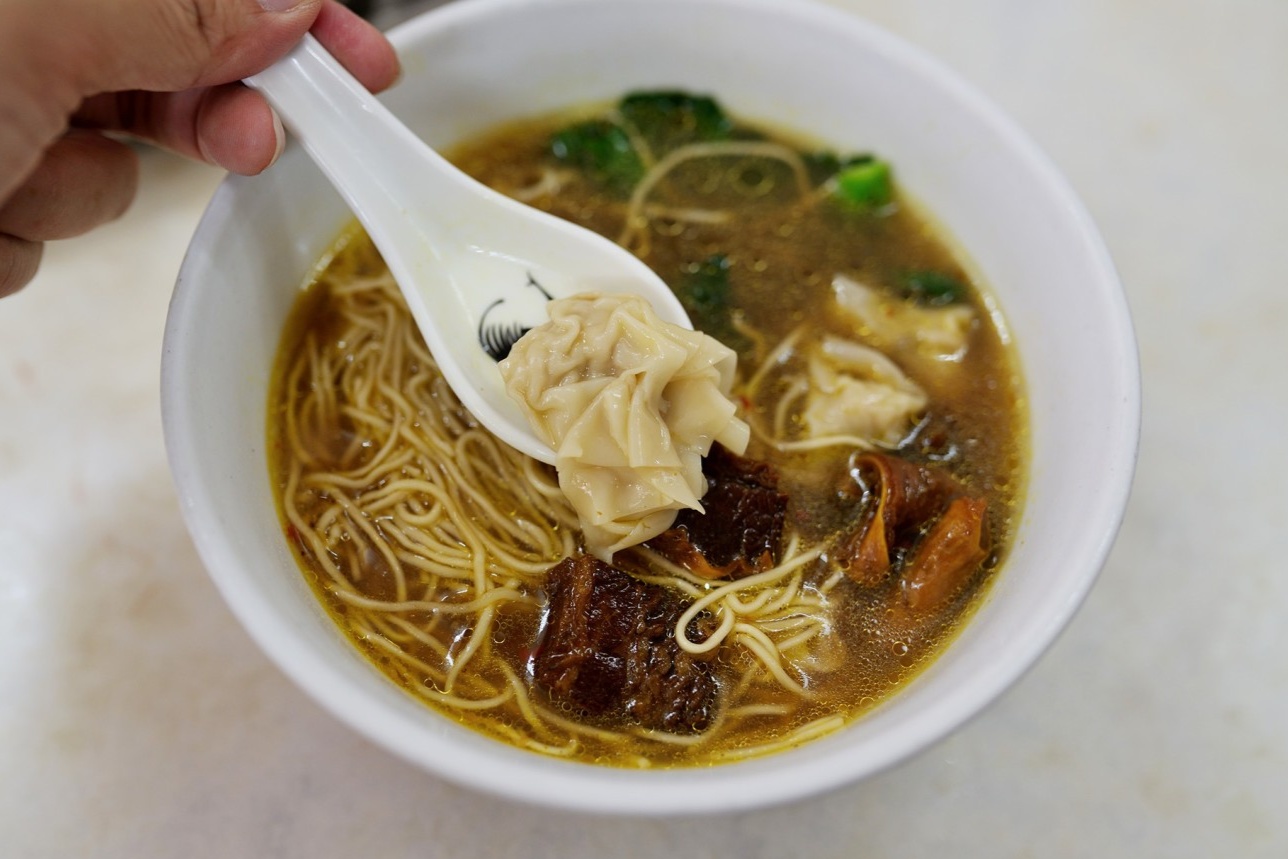  A classic bowl of Wonton Noodles from Jianguo. The clear, glistening broth, the thin yellow egg noodles, and the plump wontons should be clearly visible in a simple porcelain bowl.