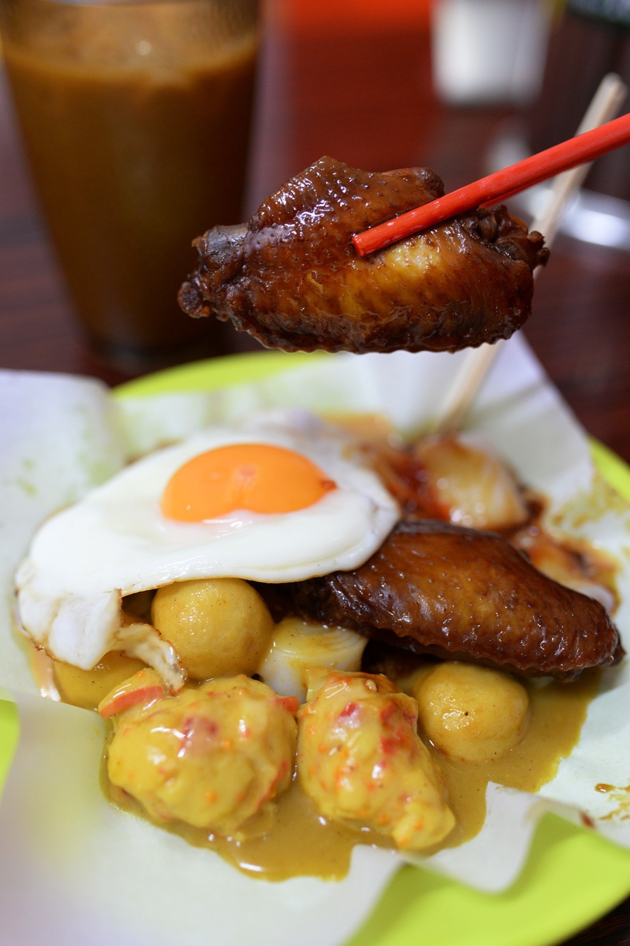  A close-up action shot of a fork or chopsticks breaking the yolk of the sunny-side-up egg, with the golden yolk starting to run over the rice noodle rolls.