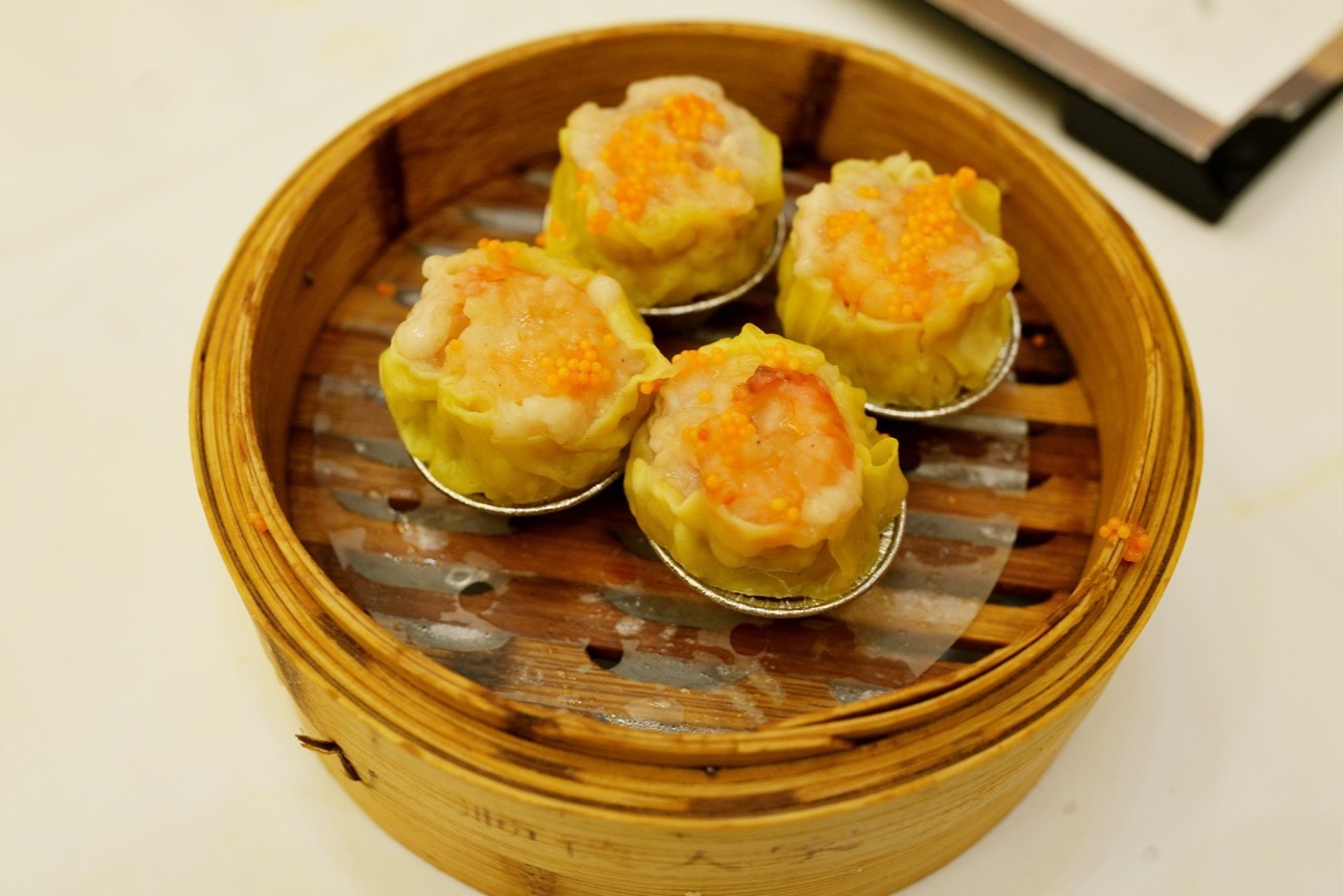  A close-up of the Crab Roe Siu Mai in a steamer. Each dumpling is plump, topped with a whole shrimp and bright orange crab roe.