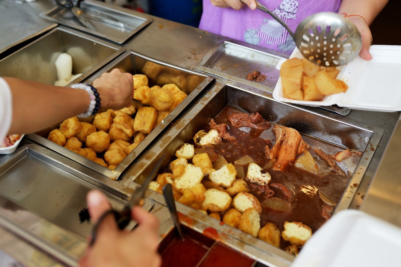  A close-up shot of the beef offal being scooped from the large simmering pot, showing the rich, dark color of the broth and the texture of the tripe and intestines.