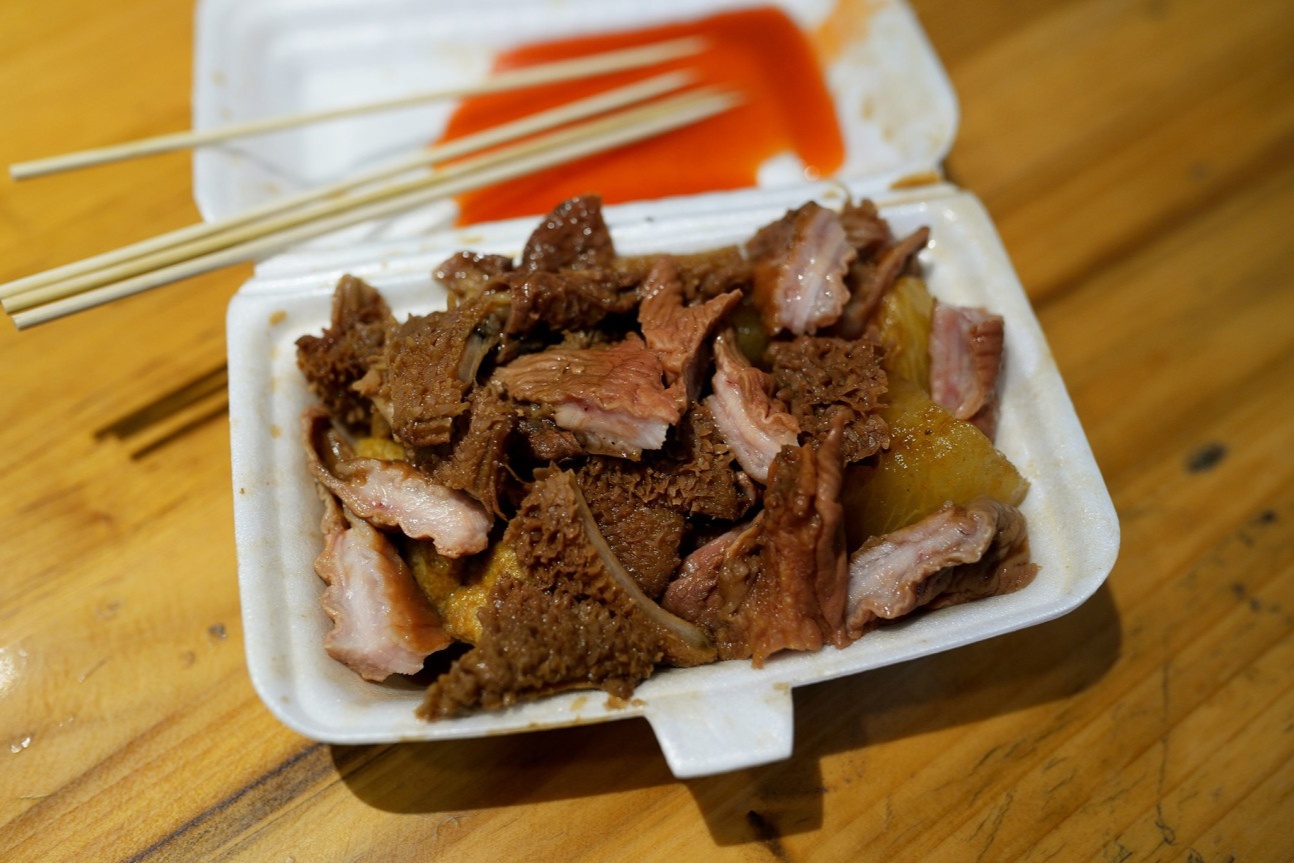  A paper bowl filled with the finished five-spice beef offal, radish, and tofu puffs, ready to be eaten on the street.