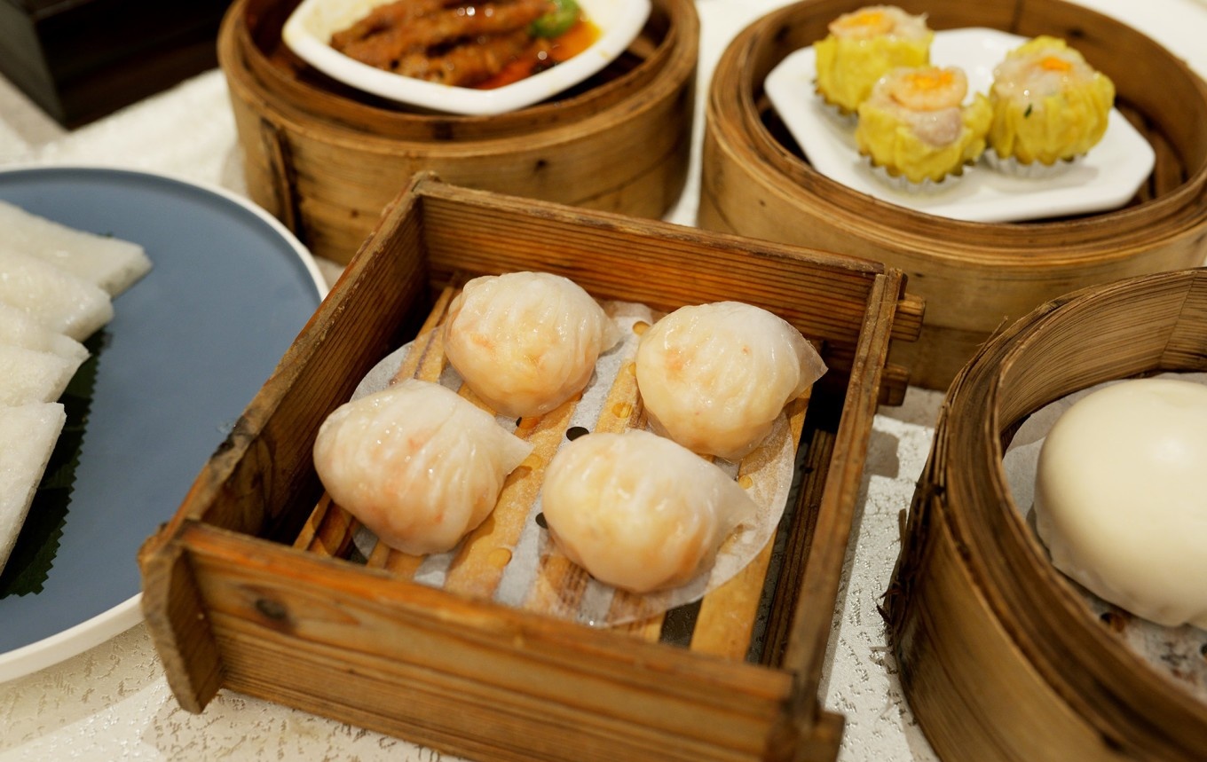  A vibrant, bustling scene inside the dim sum hall at Long's, with families at round tables and servers navigating the space with trays or carts.