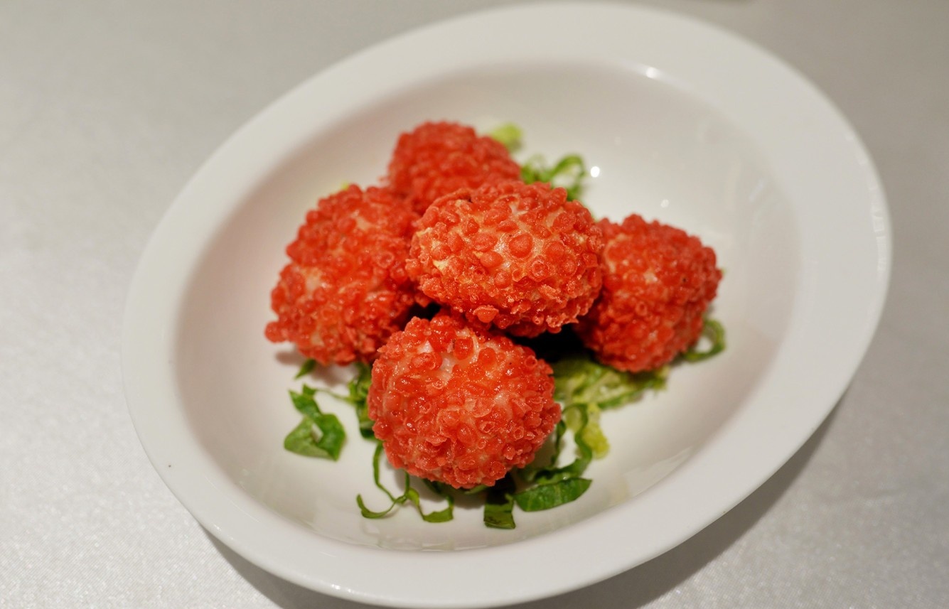  The Imperial Concubine Lychee Balls artfully arranged on a plate, looking exactly like fresh red lychees, showcasing their whimsical and brilliant presentation.