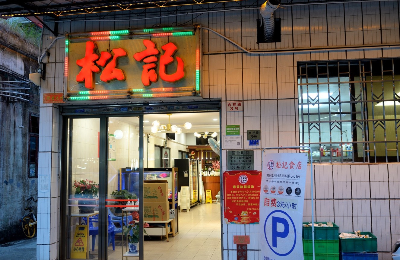  The bustling, brightly lit entrance of Song Kee Eatery at night, with patrons waiting outside, conveying its popularity.
