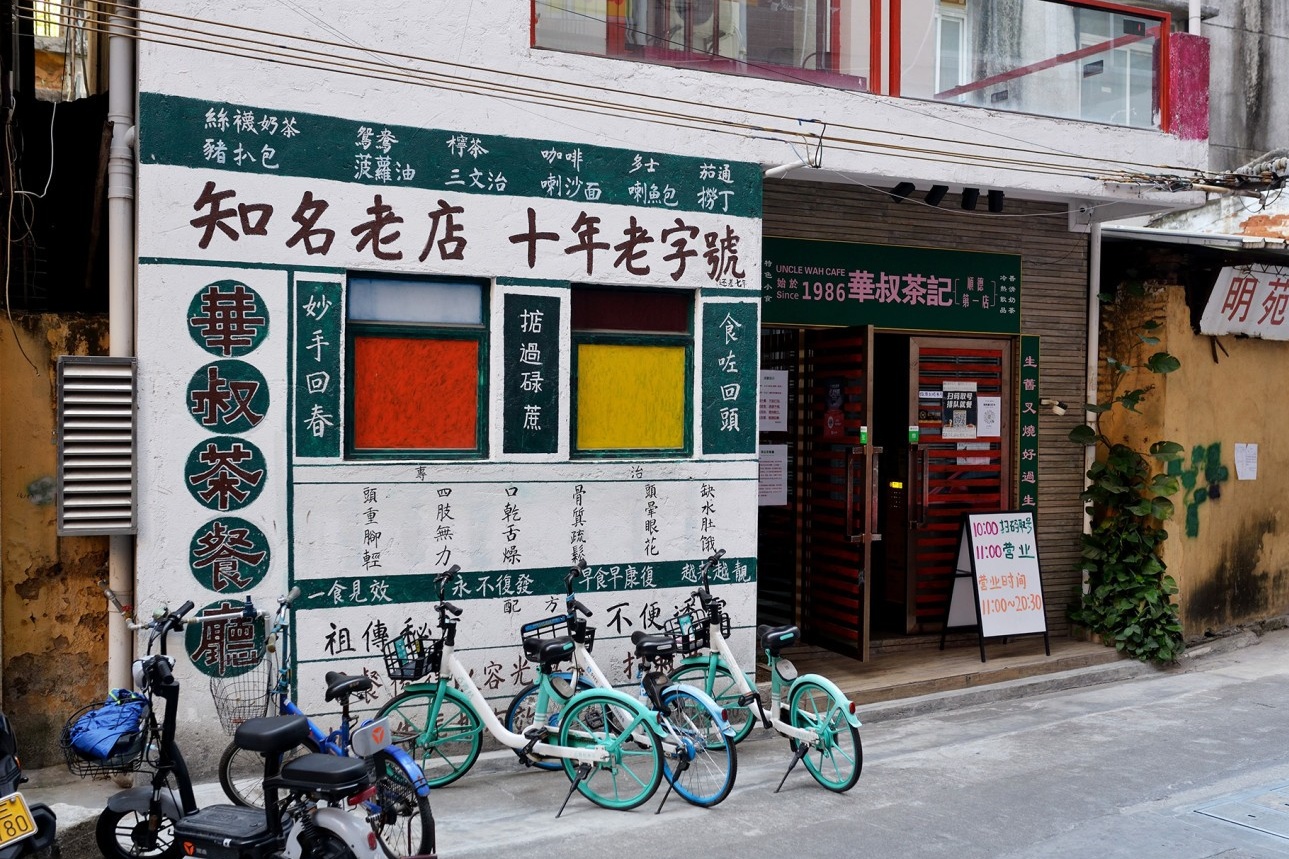  The entrance of Uncle Hua's Cha Kee, located in a narrow alley. The sign with the humorous 10-year-old brand slogan is visible, conveying its trendy and hidden-gem character.