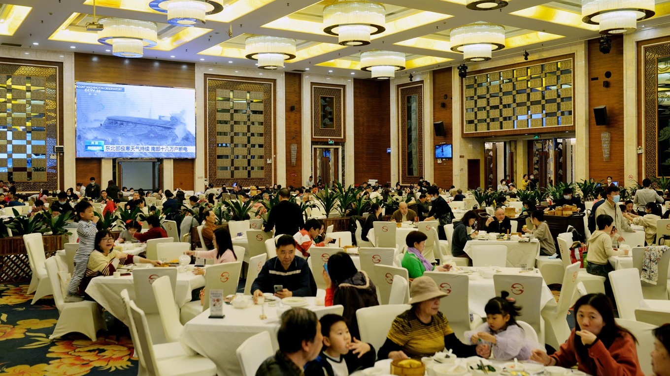  The grand, bustling dining hall of Shunde Renjia Restaurant, with large round tables filled with guests enjoying dim sum, conveying a classic, upscale yum cha atmosphere.