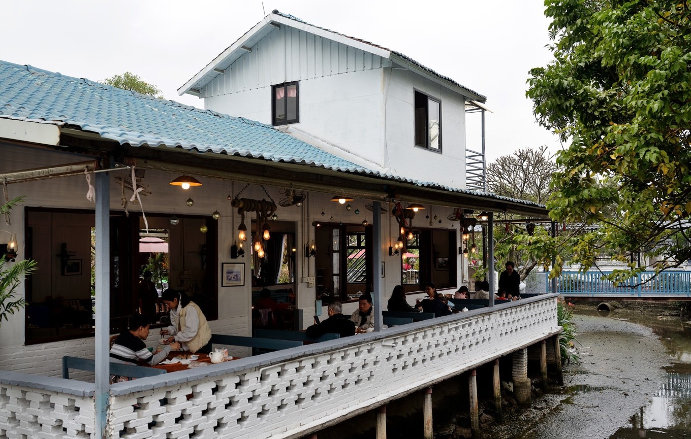  The serene, garden-like environment of Tianranju, with tables set in a courtyard next to a small, calm river, creating a peaceful dining atmosphere.