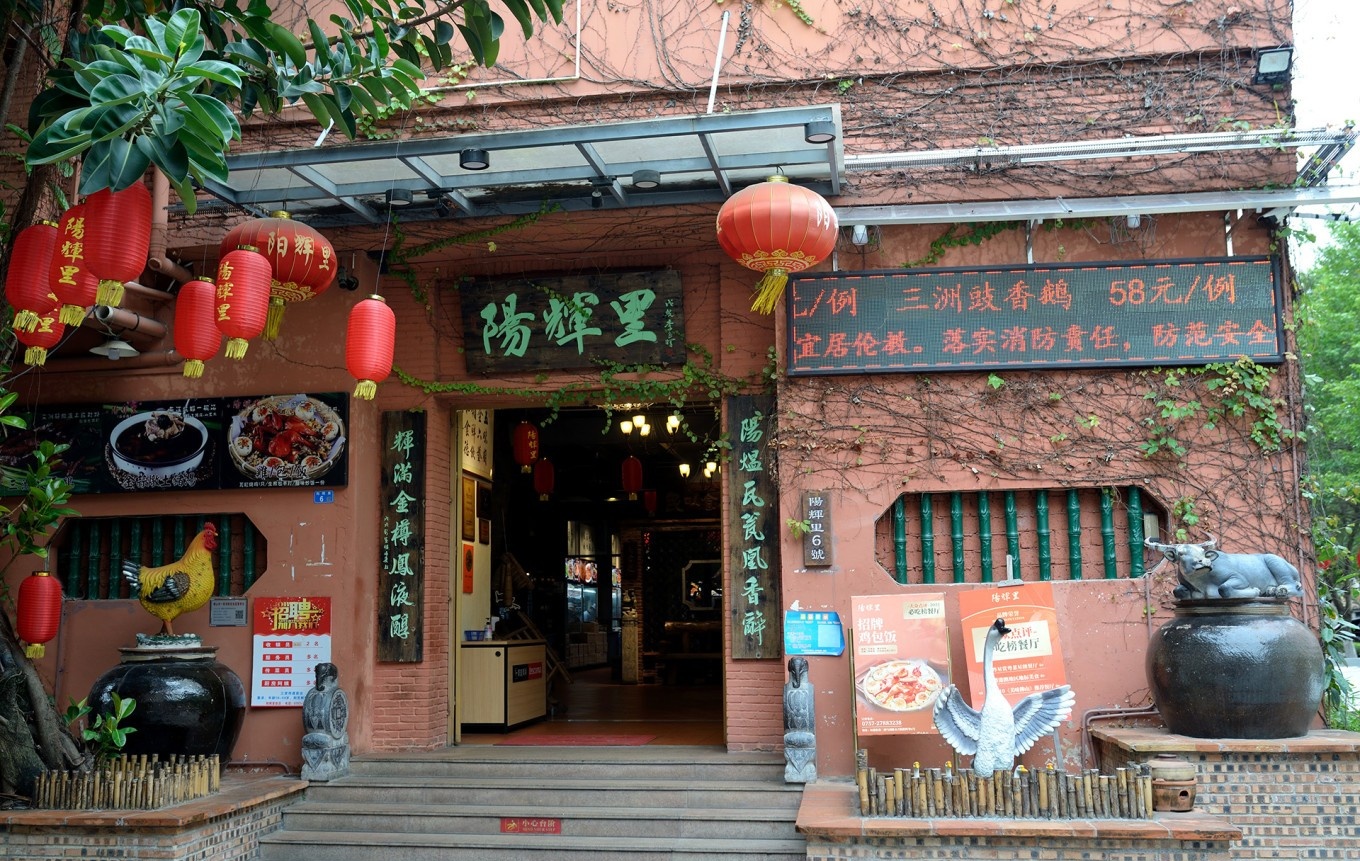  The unique interior of Yanghuili, showcasing the high ceilings, exposed red brick walls, and industrial-chic decor of the renovated factory building. Diners are enjoying their meals.