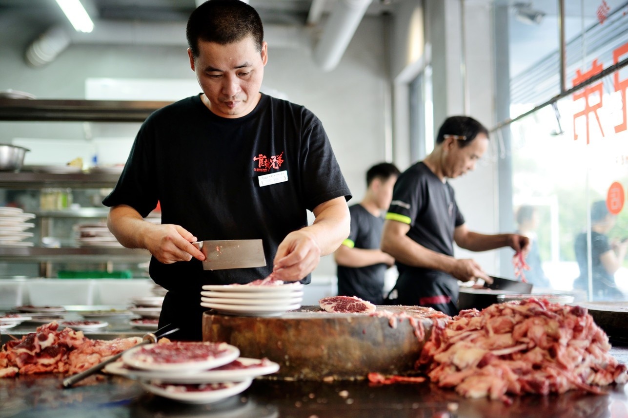  A bustling, brightly lit open kitchen where skilled butchers are expertly slicing large cuts of beef.