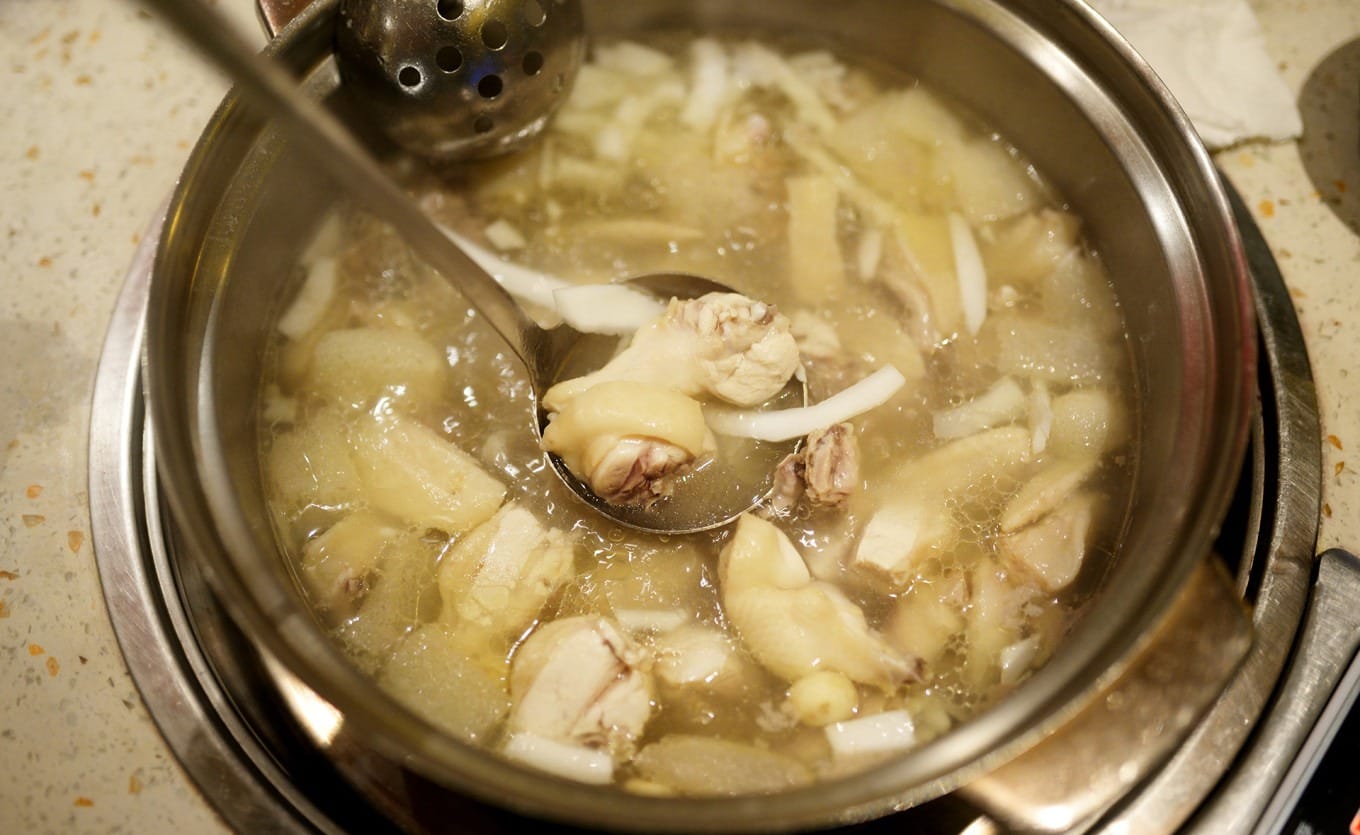 Clear coconut chicken broth simmering with bamboo fungus and water chestnut