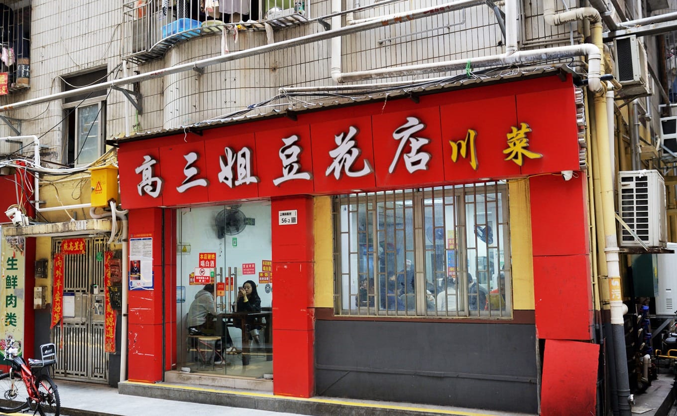 Crowded interior of Gao Sanjie Douhua Rice Shop under a residential building in Shangmeilin