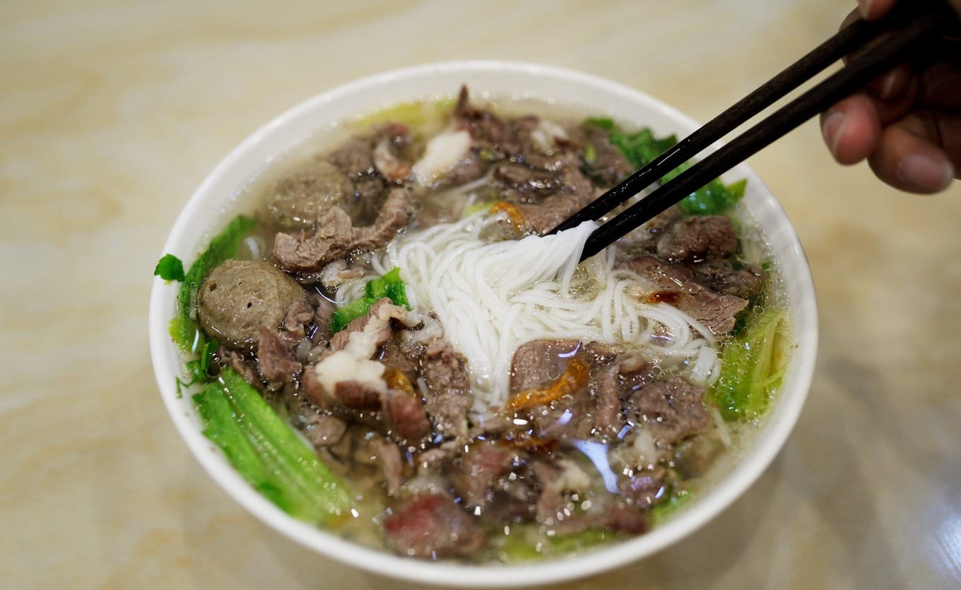 Fresh beef guo tiao soup with beef slices, meatballs, and greens