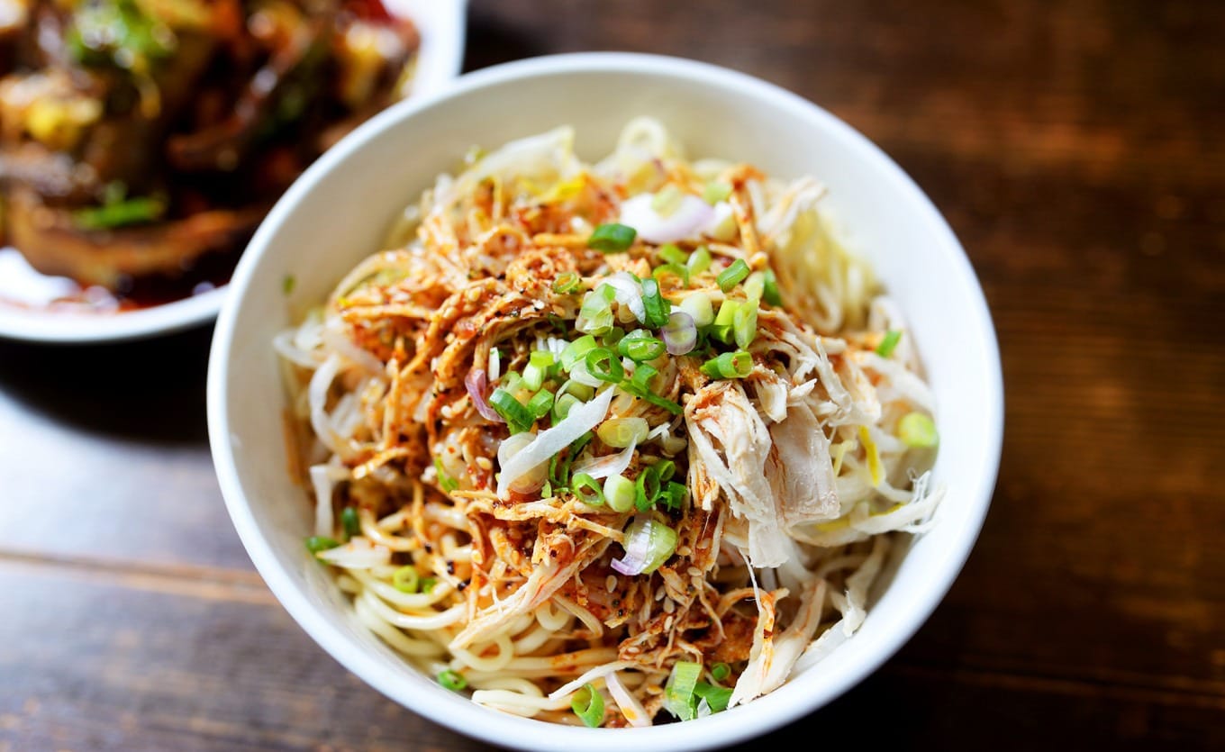 Shredded chicken cold noodles with vibrant red chili oil, sesame, and scallions