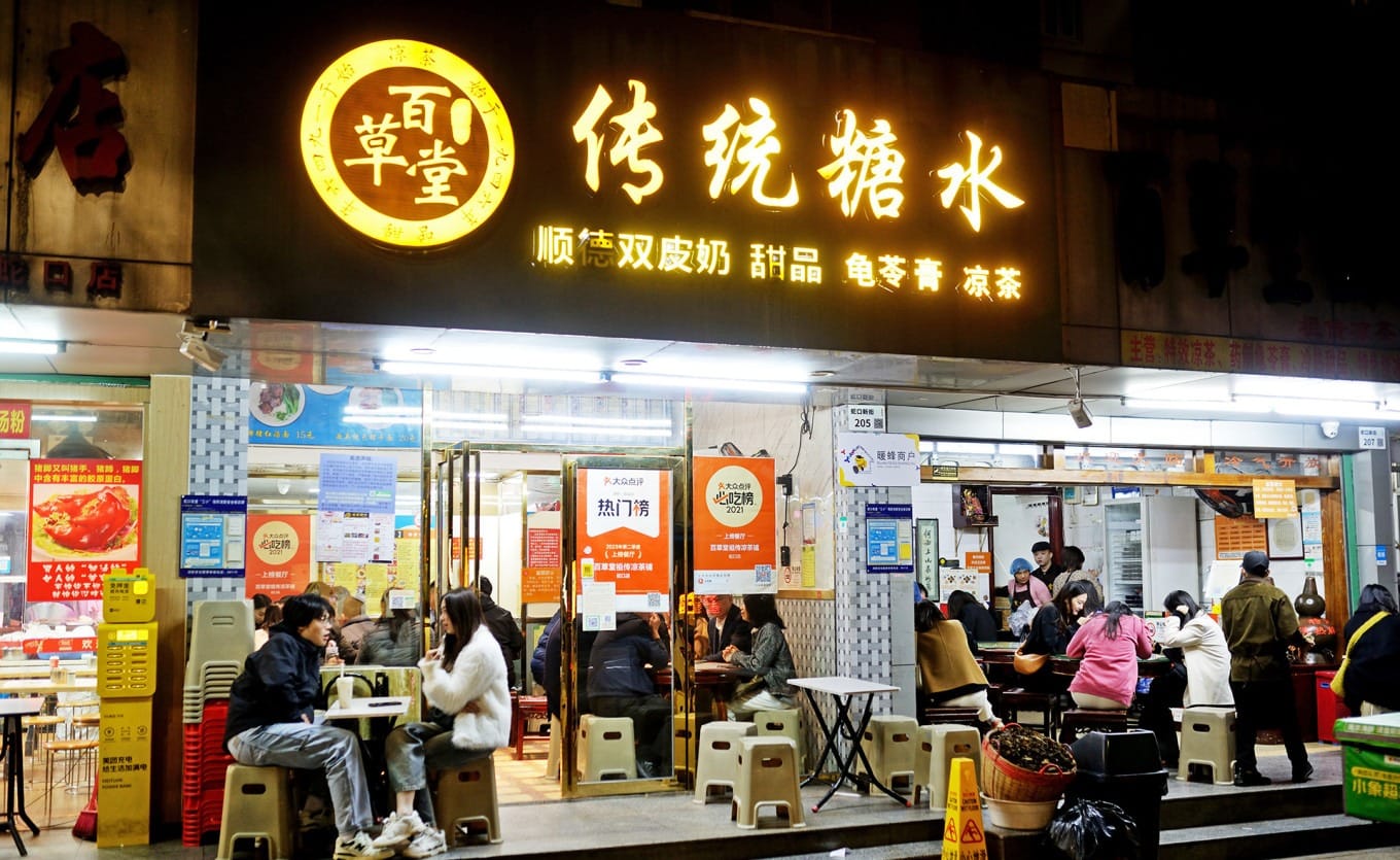 Crowded evening scene at Baicaotang Ancestral Herbal Tea Shop in Shekou