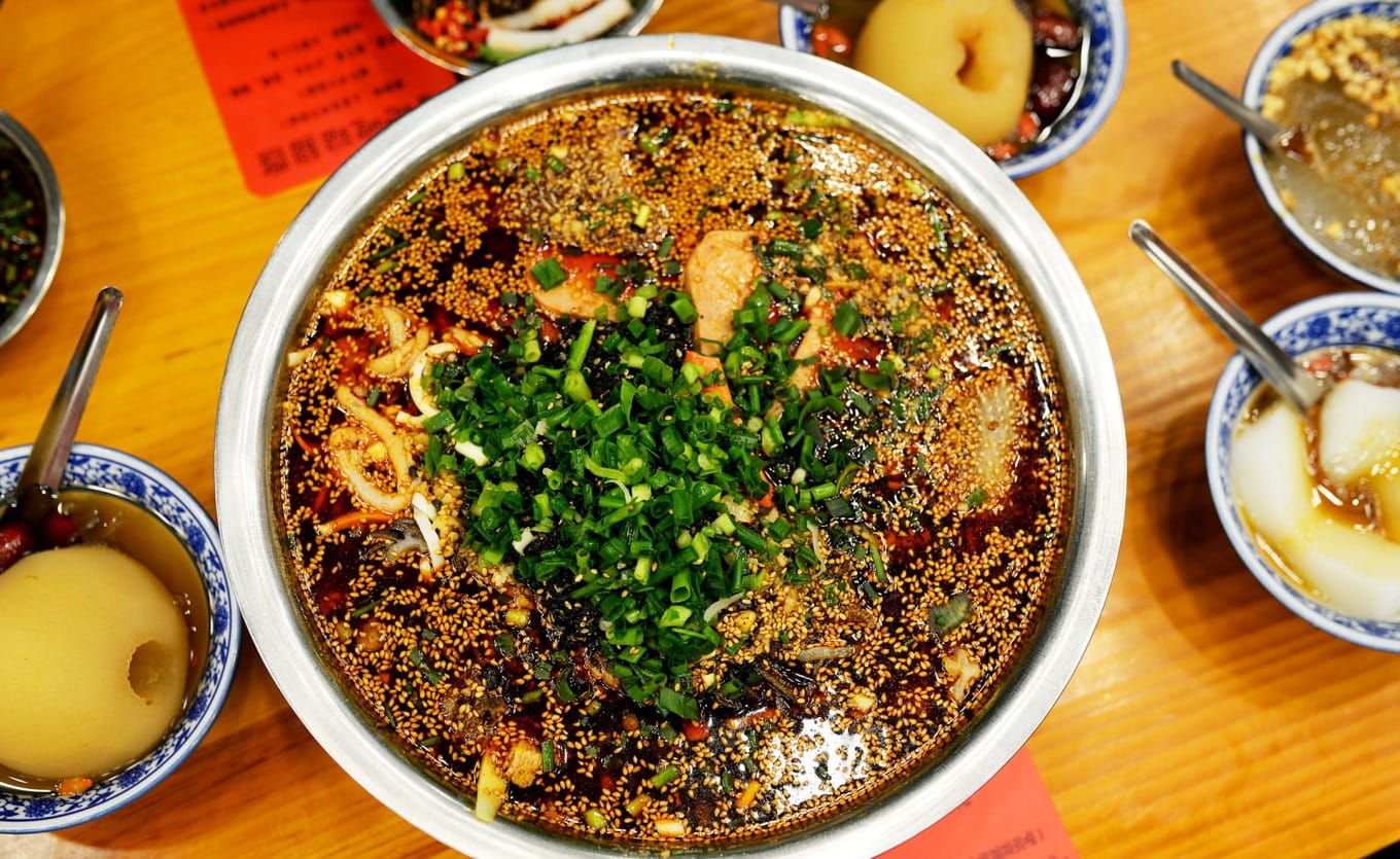 Large stainless-steel bowl filled with mao roast duck and assorted ingredients