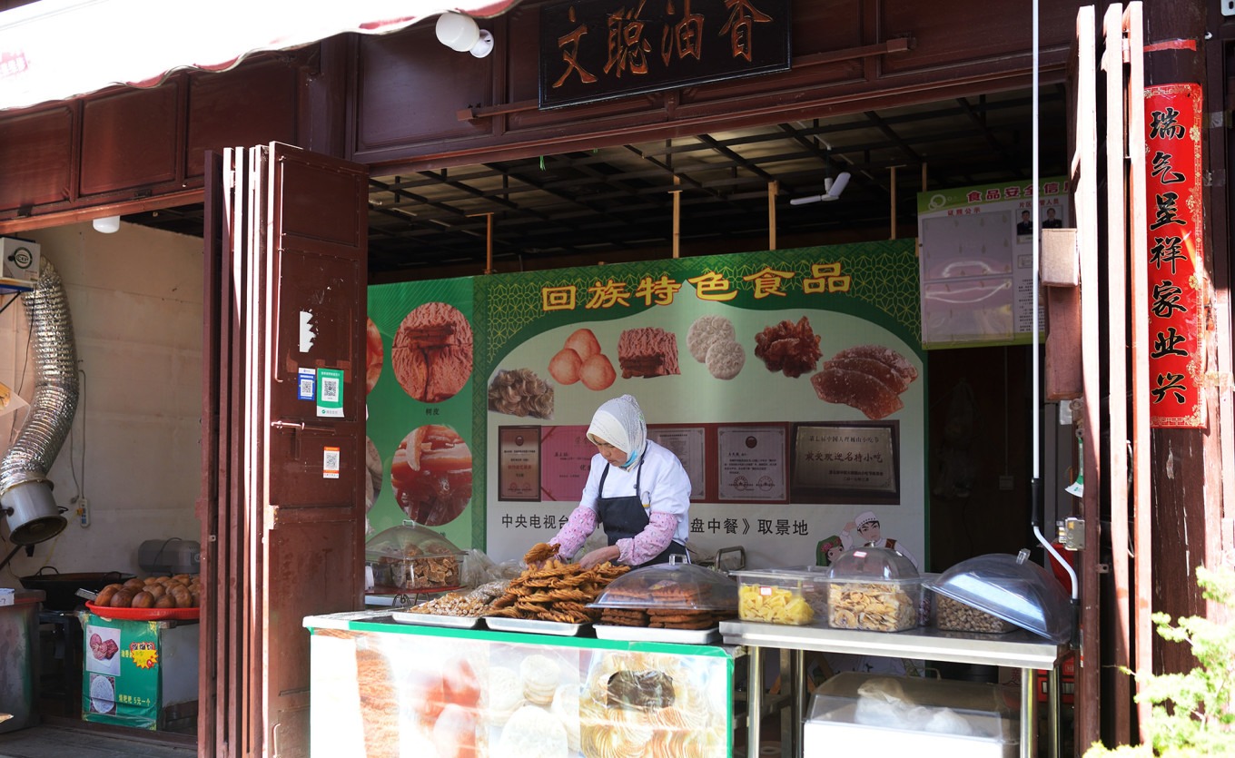A vendor preparing oil-fried bread dough at Wencong Oil-Fried Bread shop in Weishan