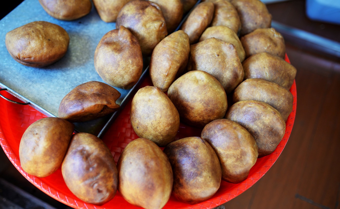 A close-up of a freshly fried, golden-brown oil-fried bread with a soft, airy texture
