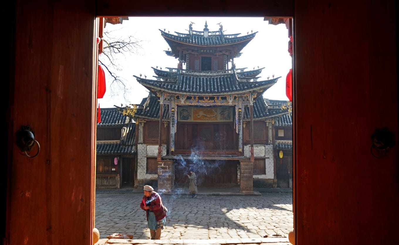 Guardian statues at the temple gate, one blue and one red, depicting fierce expressions