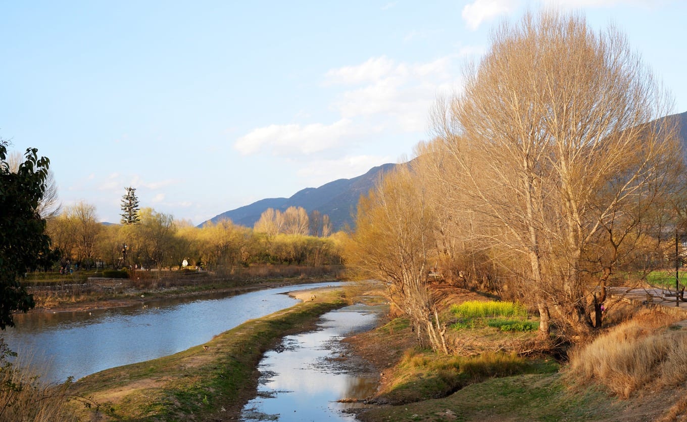 Tourists walking across Yujin Bridge with traditional architecture in background