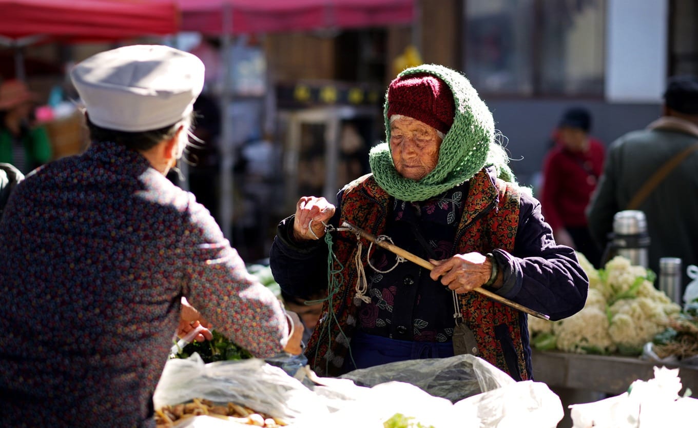 Local Bai women in traditional dress shopping at the market