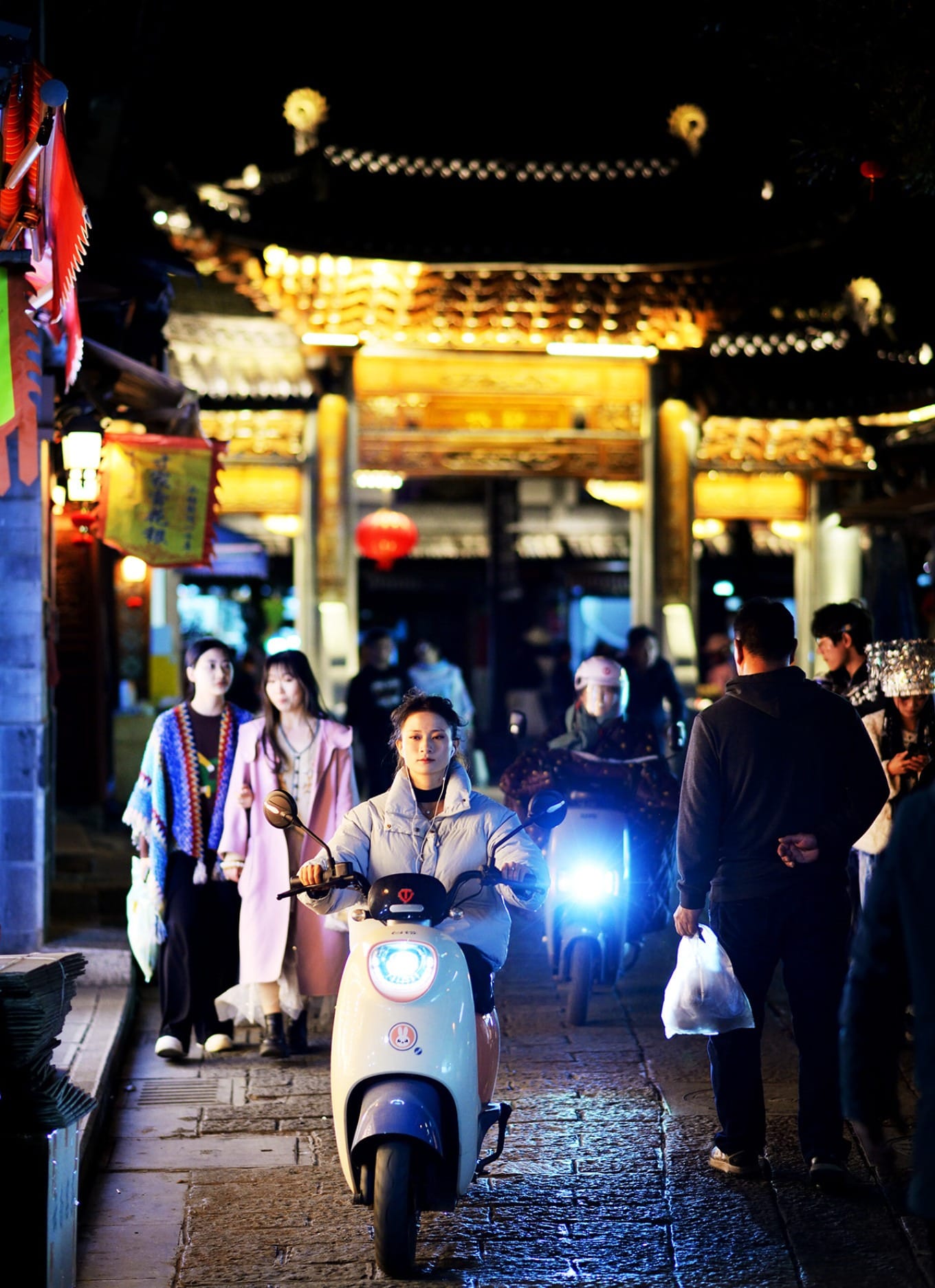 A person standing in a vast, sun-drenched wheat field with rolling hills and traditional houses in the background
