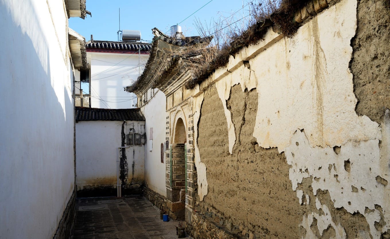 A quiet, narrow Xizhou street at dusk with traditional houses and soft glowing lantern light