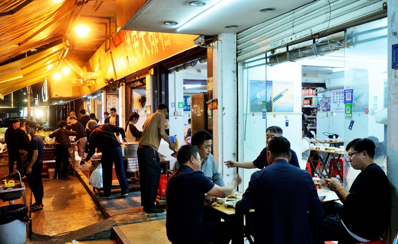 Crowded exterior of Jin'an Street Dai Pai Dong at night with diners seated at tables