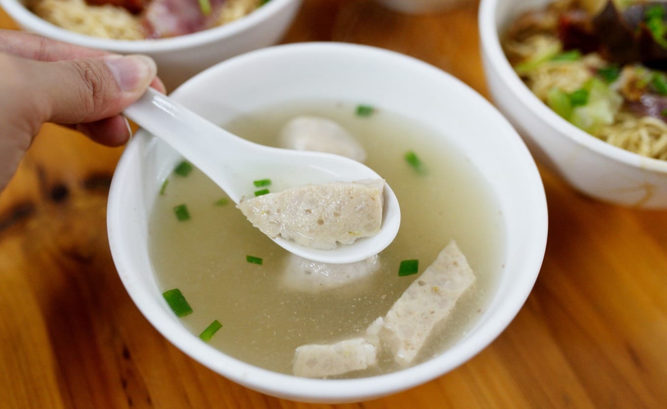 Clear pork bone broth with pork balls served as traditional accompaniment