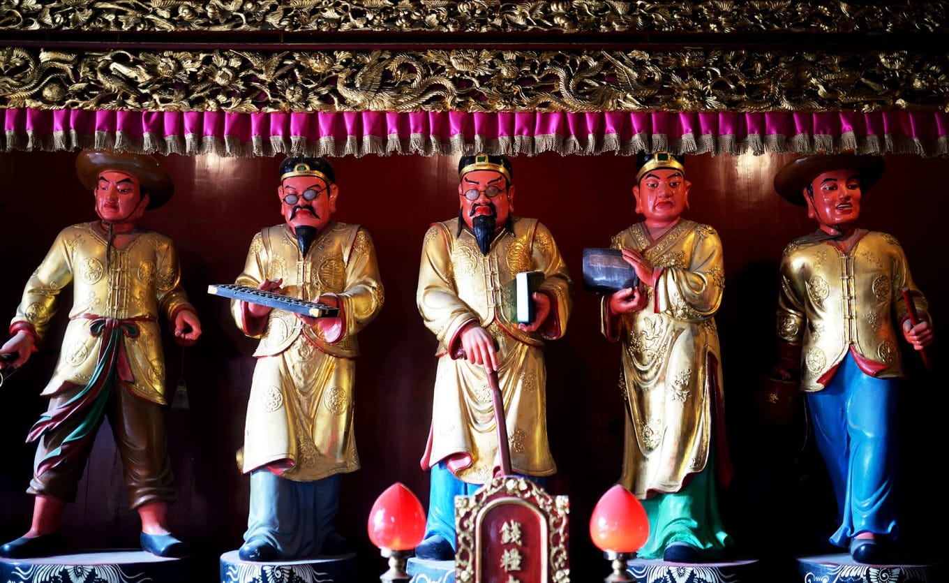 Side chambers housing additional deity statues including wealth and earth gods