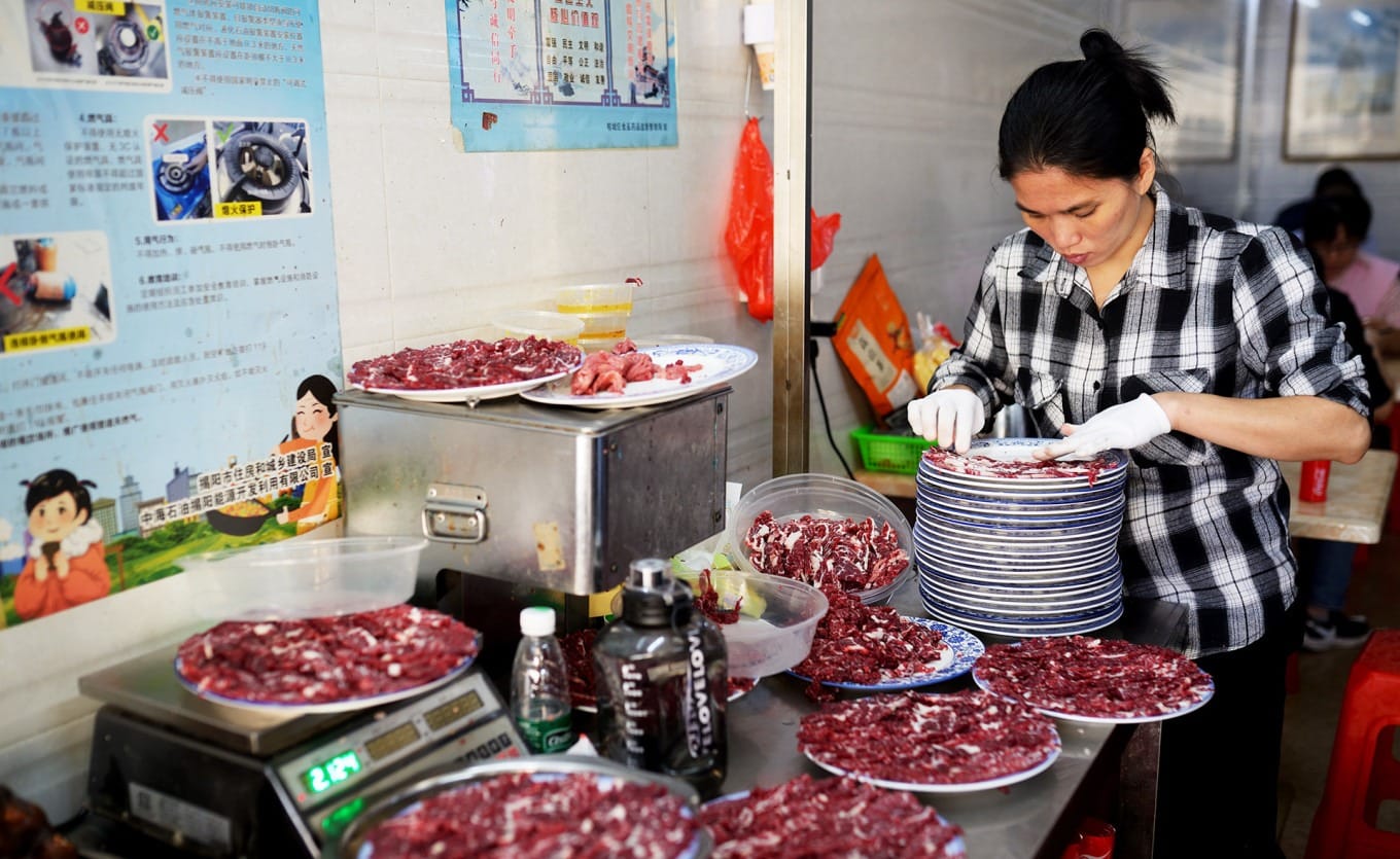 Chef hand-slicing fresh beef with traditional cleaver at Lu Ji