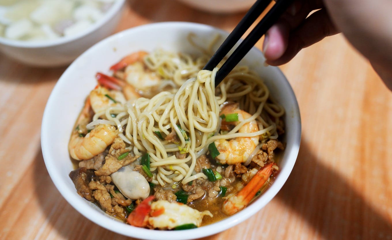 Close-up of mixed lo mein noodles coated in thick savory sauce with bean sprouts