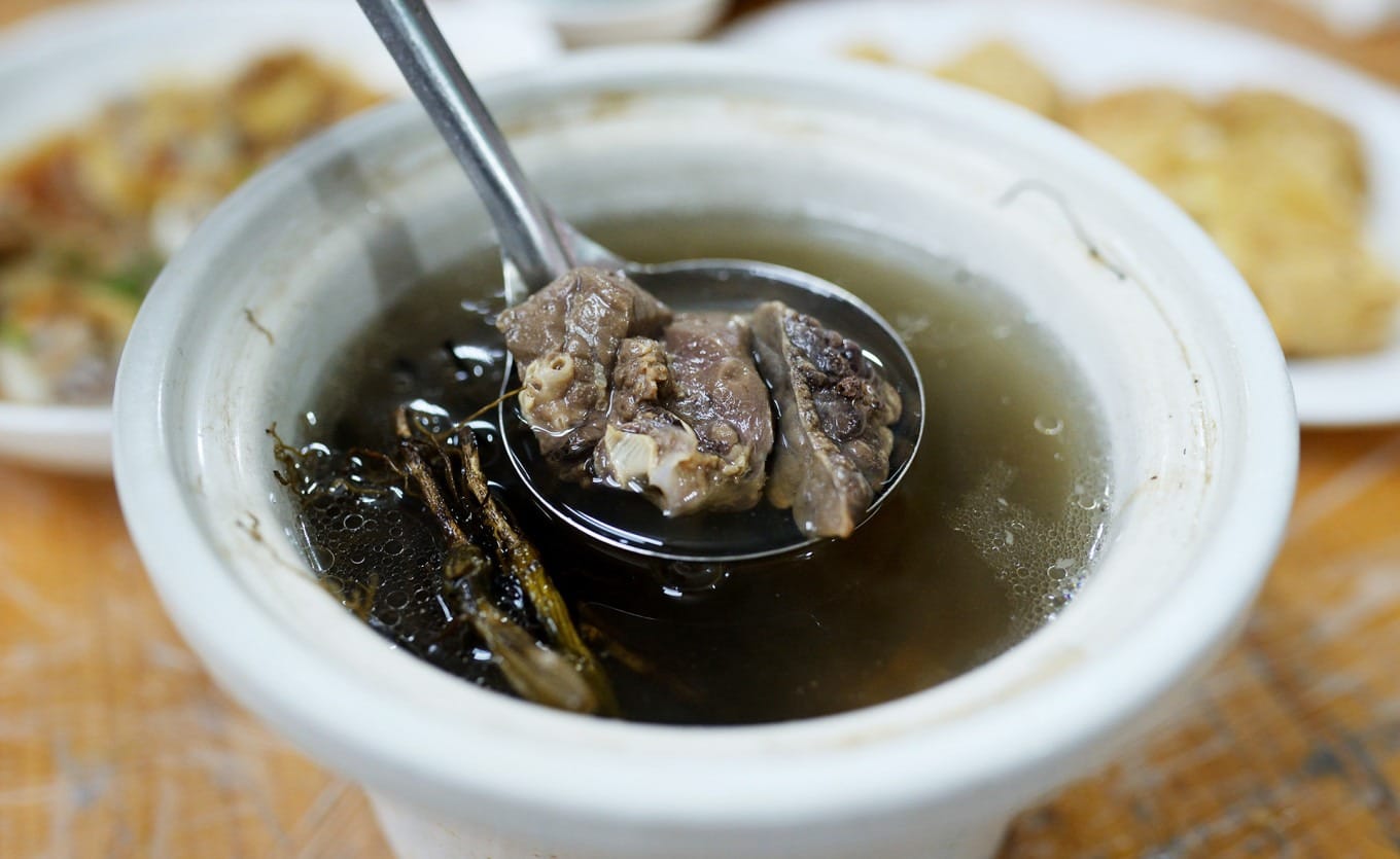 Stone olive and pig lung soup served in a traditional ceramic bowl
