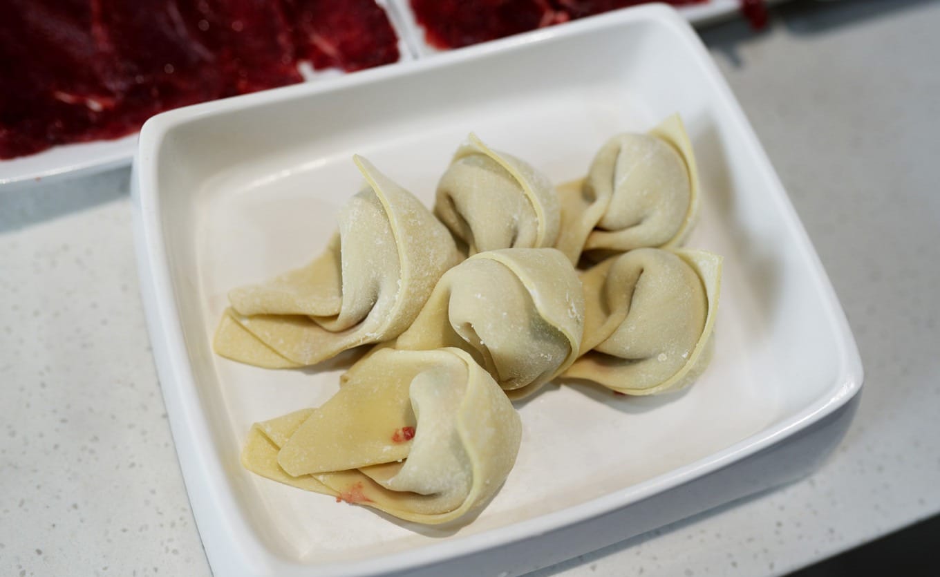 Pan-fried beef dumplings with golden crispy exterior on white plate