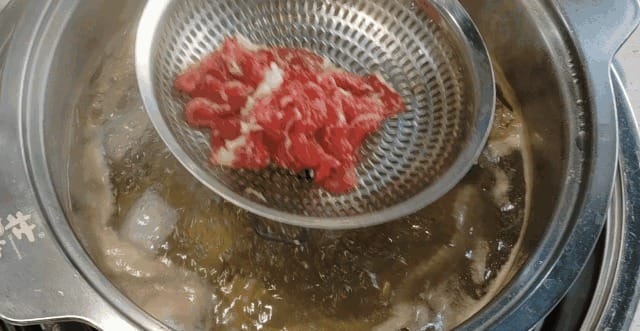 Marbled beef slices displayed on traditional round wooden tray