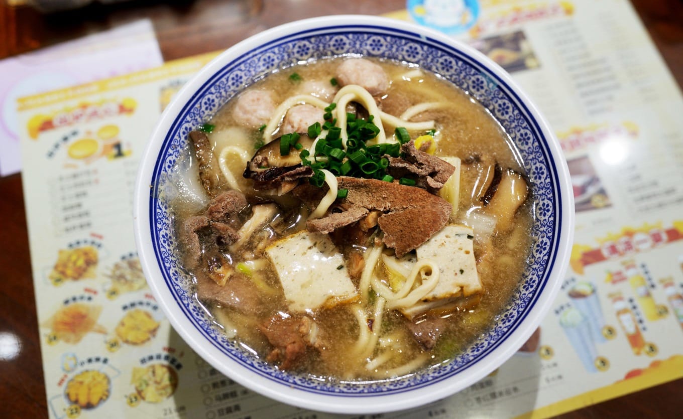 A bowl of traditional wet noodles with various toppings