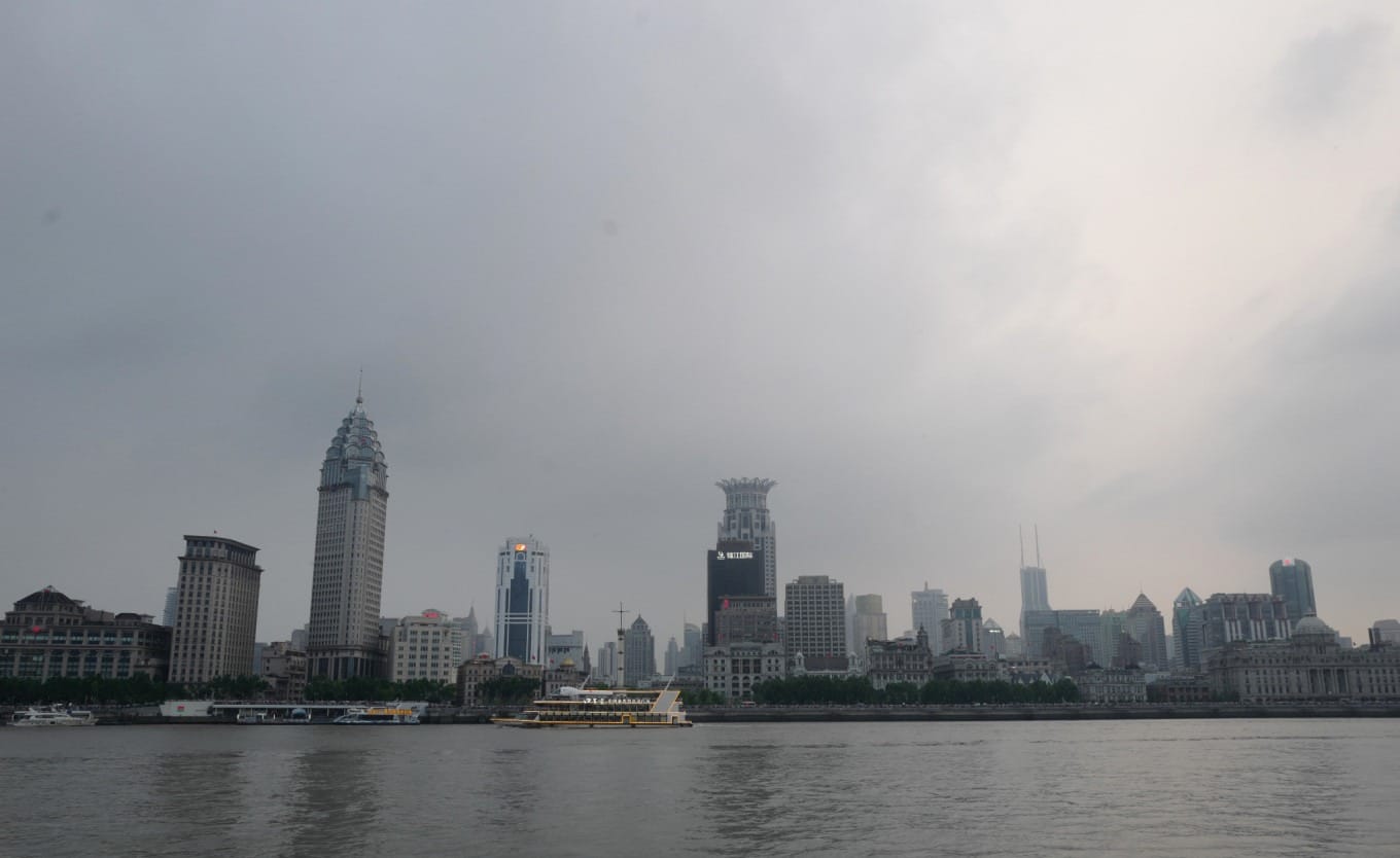 Crowded viewing area along Shanghai's Huangpu River waterfront at dusk