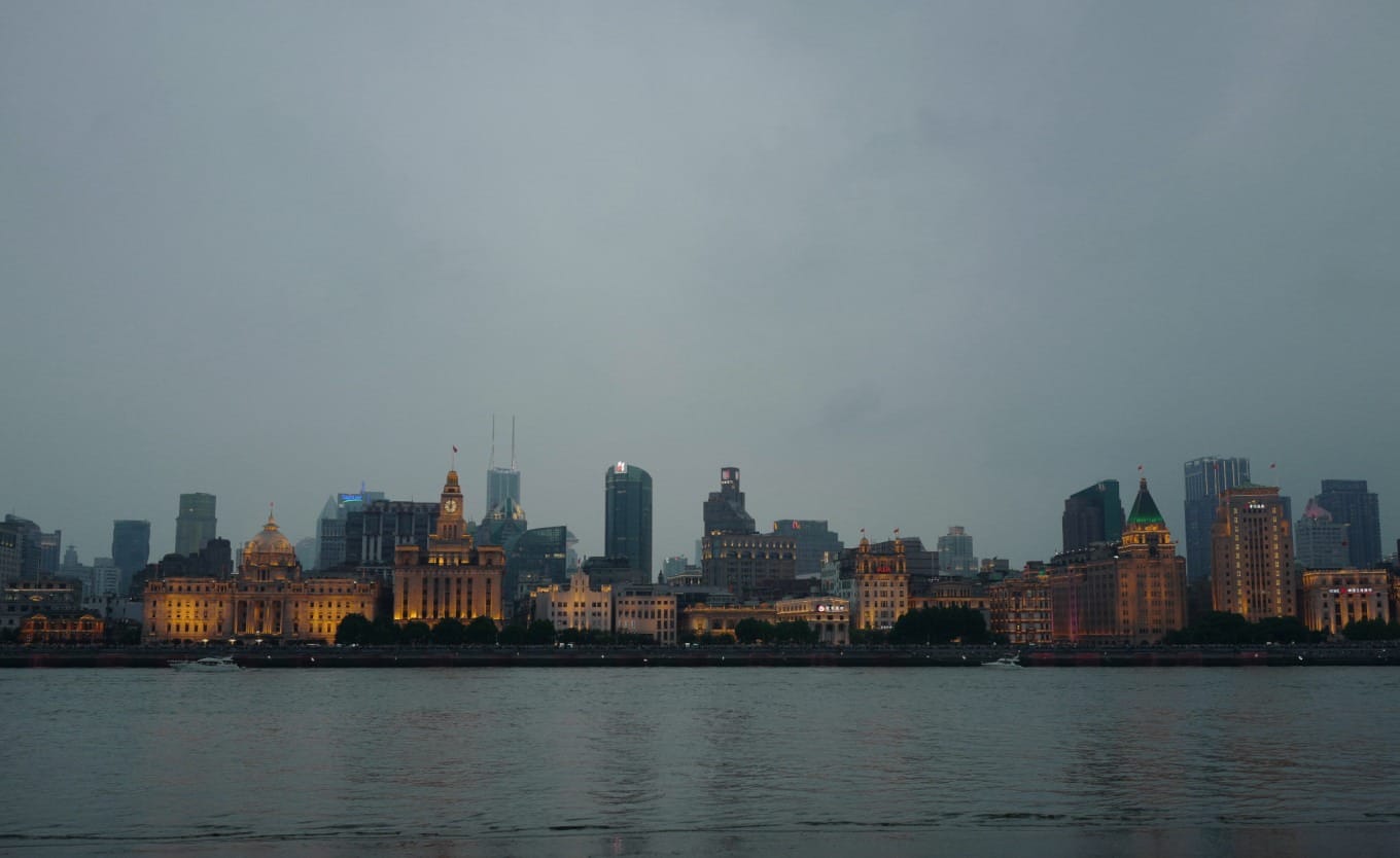 Historic Bund buildings illuminating at dusk across the Huangpu River from Pudong