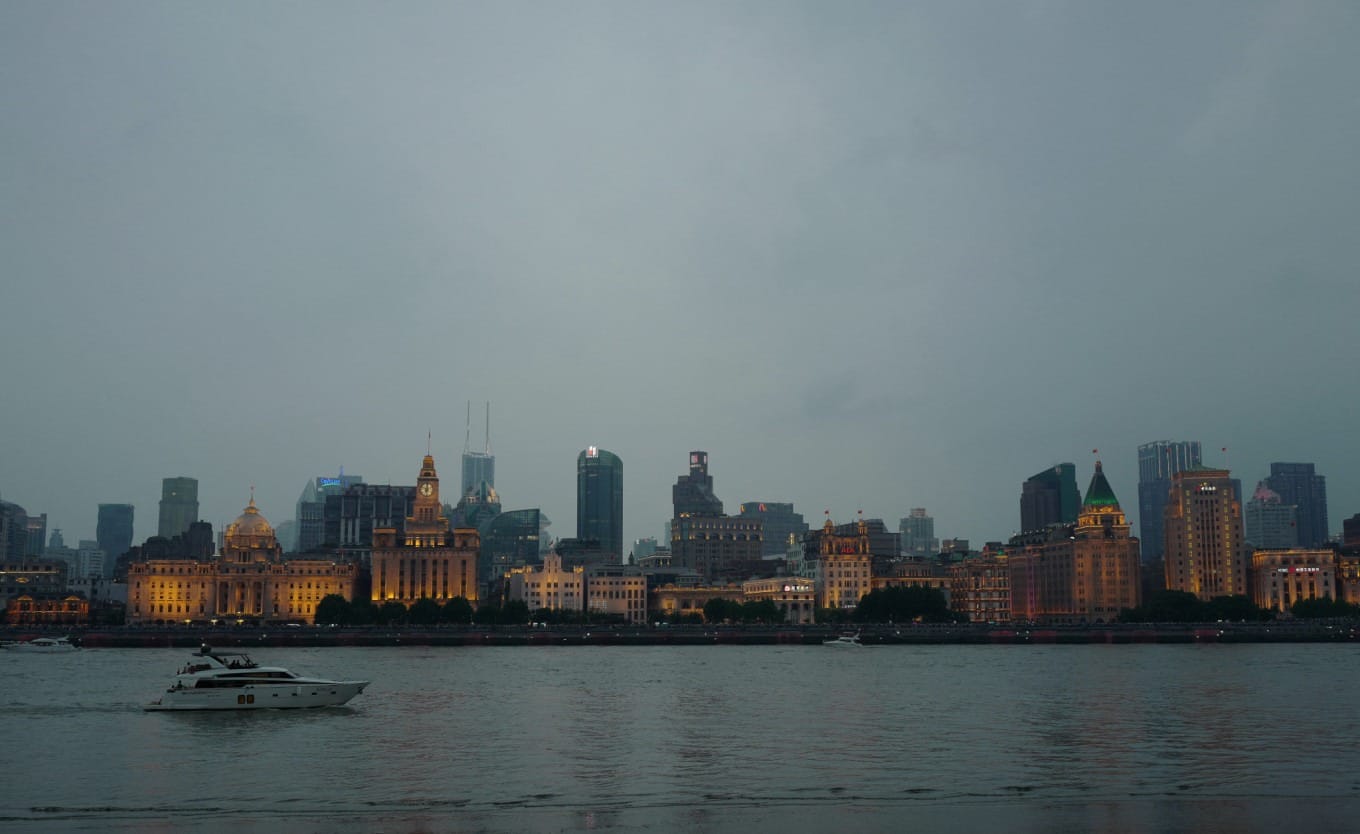 Cargo ships and tourist boats navigating the Huangpu River at twilight