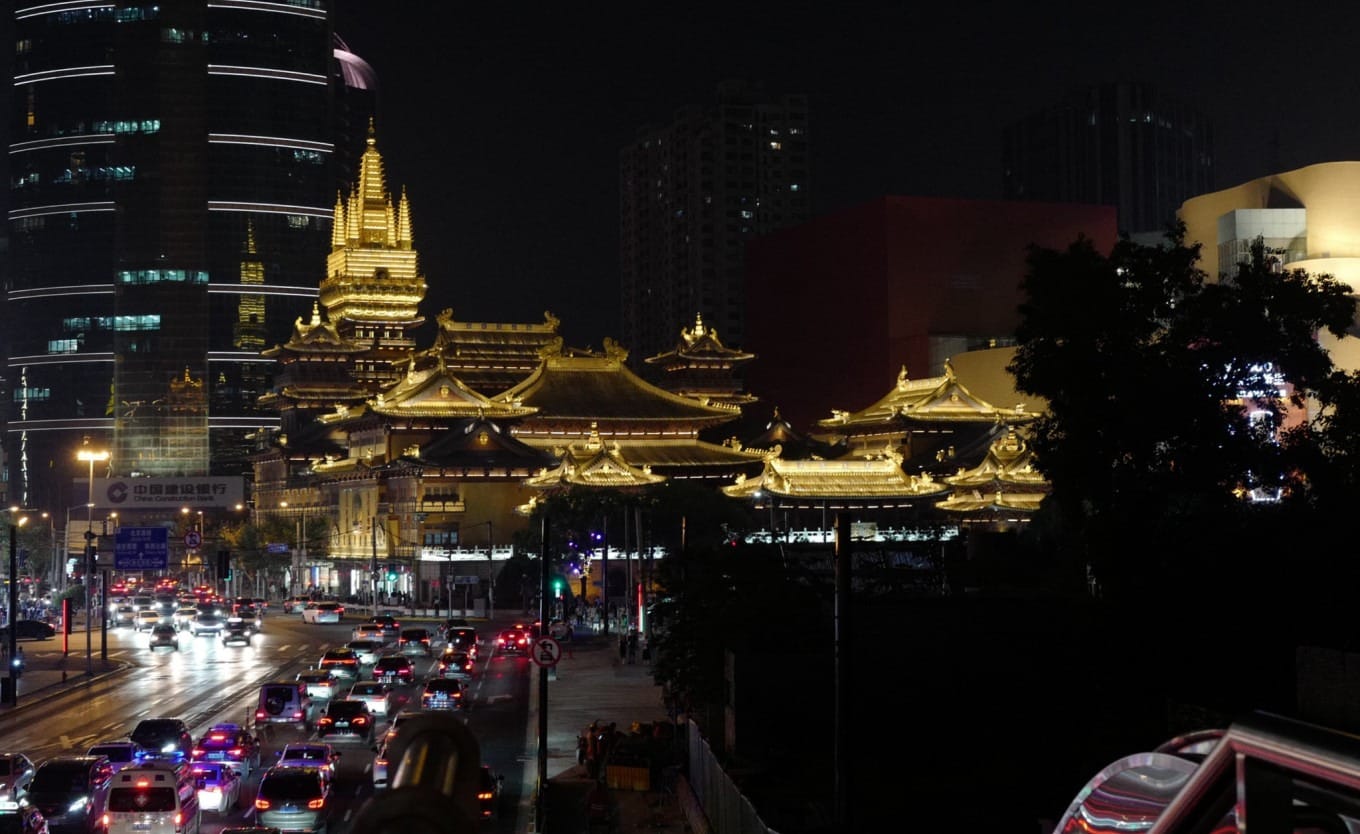 Jing'an Temple with a large digital screen across the street displaying a slogan
