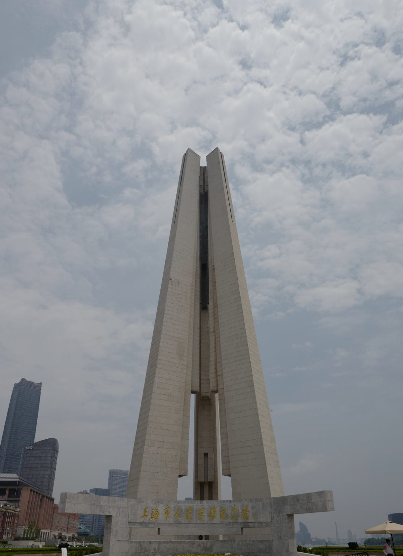 Three towering pillars of the Monument to the People's Heroes against the Shanghai skyline