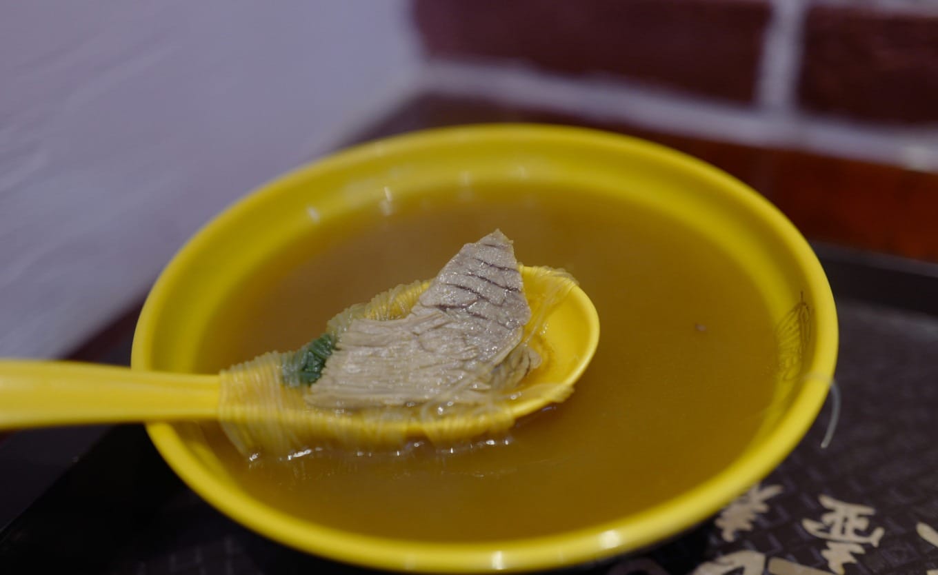 Steaming bowl of beef vermicelli soup with herbs and thin noodles