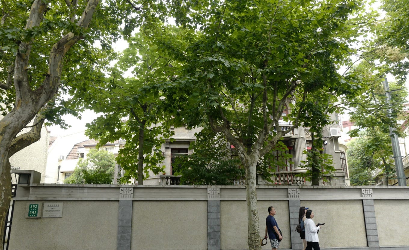 Lush trees lining Wukang Road, partially framing a historic villa