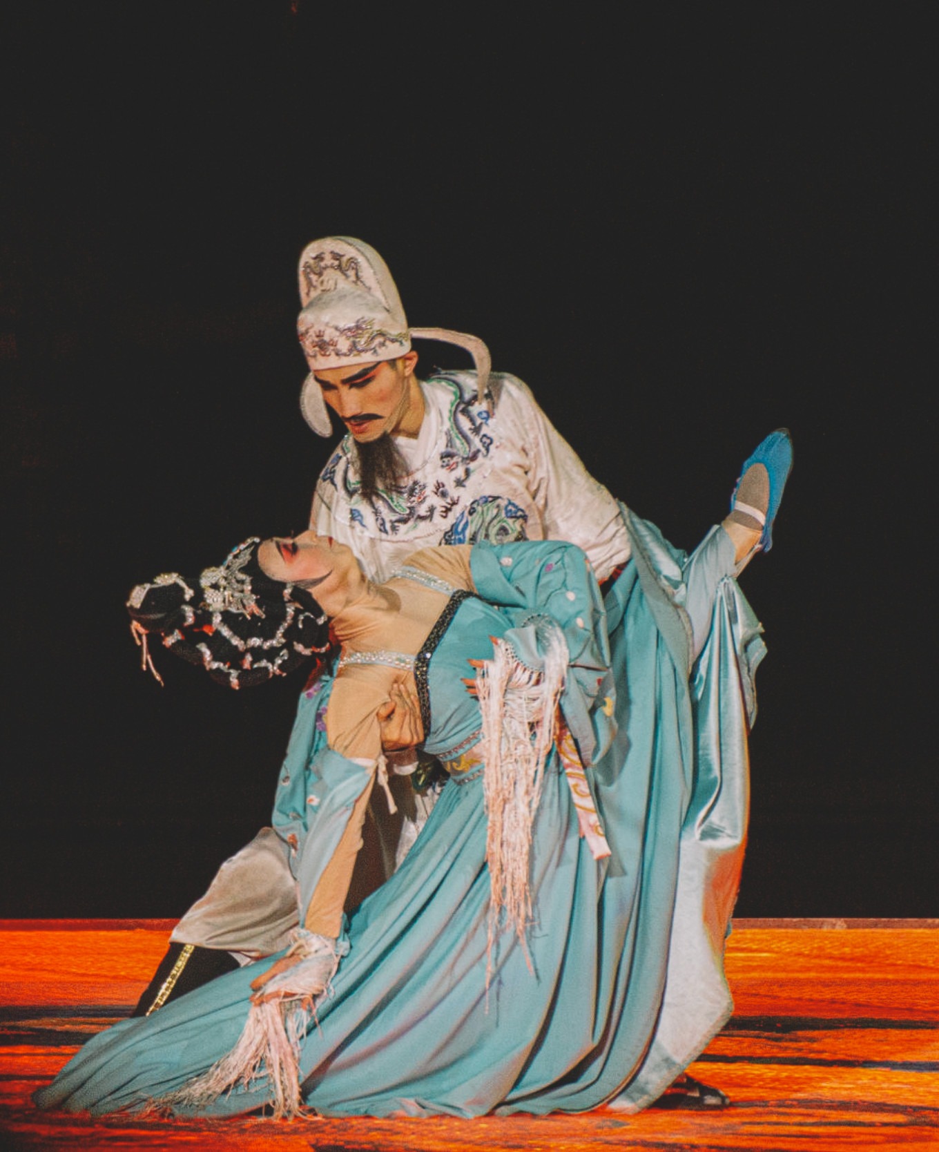 Dancers in Tang Dynasty costumes performing on stage with lake and palace
